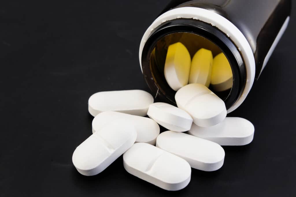 Antibiotika-Tabletten und ein Fläschchen auf schwarzem Hintergrund. Beschriftung lautet: Der Einsatz von Antibiotika sollte immer umsichtig erfolgen. Auch in der Tierhaltung.