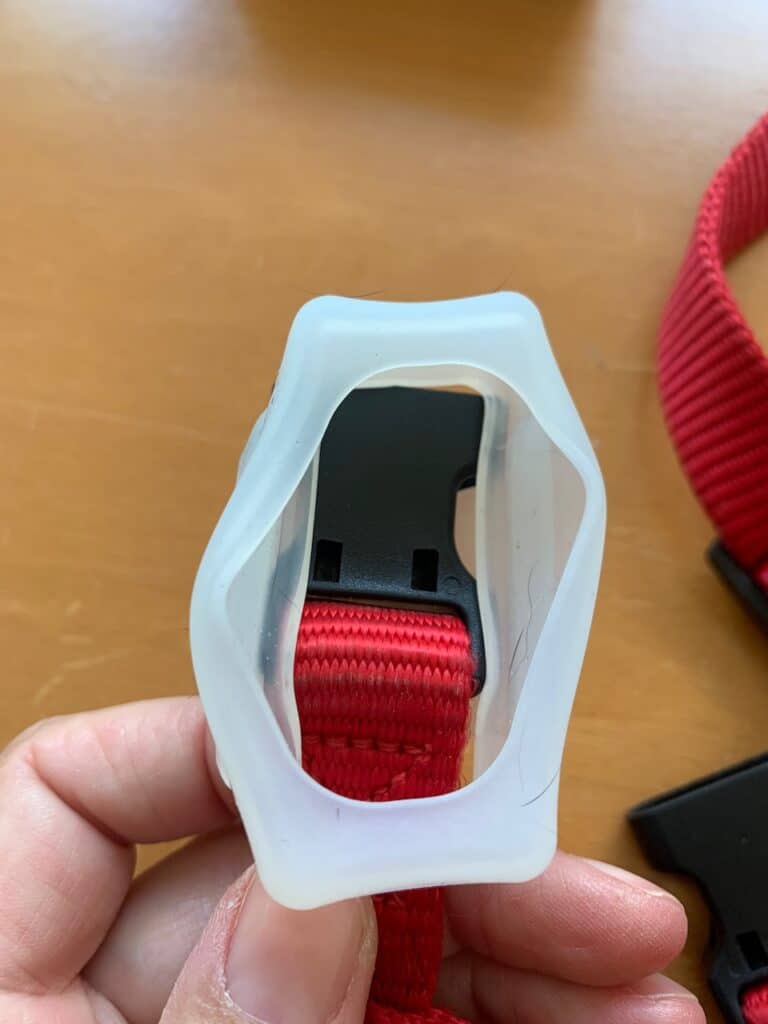 Da die Befestigung nicht zu öffnen ist, wird der Gurt einfach durchgeschoben. Sie ist flexibel genug, dass mit etwas Gefummel auch die Schnalle hindurchpasst.